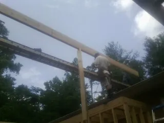 Carpenter setting a ridge beam over a new addition frame — Ice Dam Removal by Roofing Brothers in Jenison