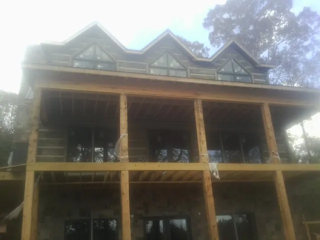 Dormers and porch framing on a large log home under construction — Roof Coating work by our crew in Jenison