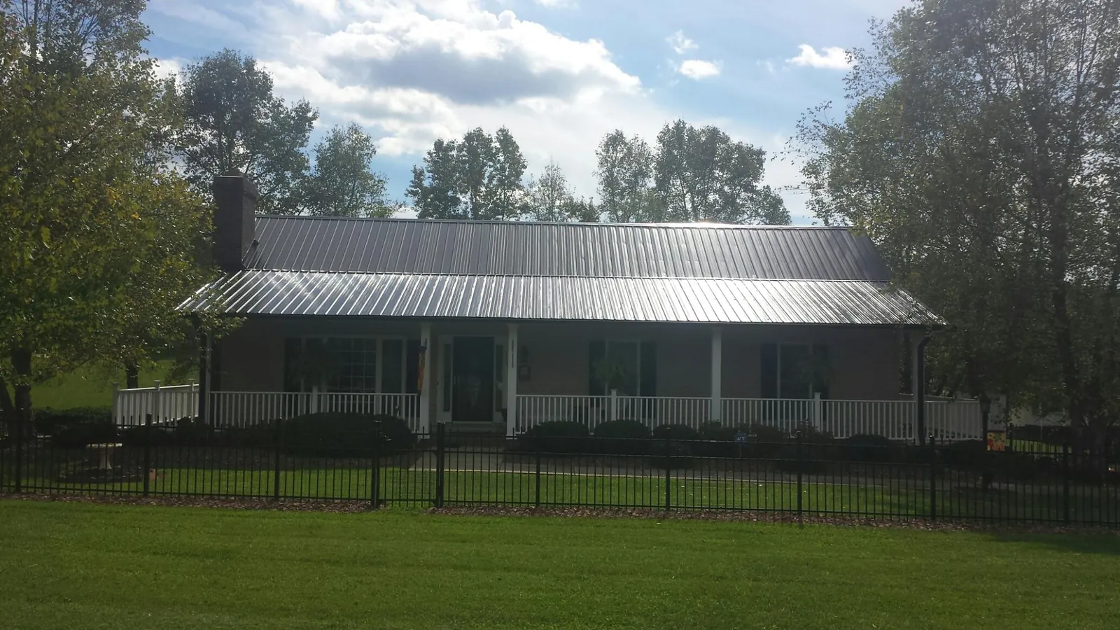 Gray metal roof on a brick ranch with a full width front porch — Gutter Guard Installation work by our crew in Jenison