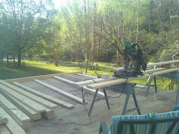 Miter saw and framing lumber on a deck under construction in Jenison