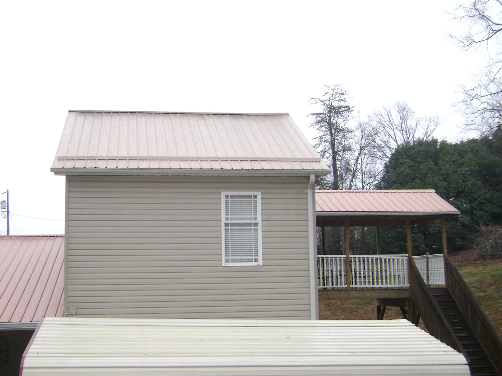 Tan metal roofs on a two story addition and attached porch, from a Roof Replacement job in Jenison