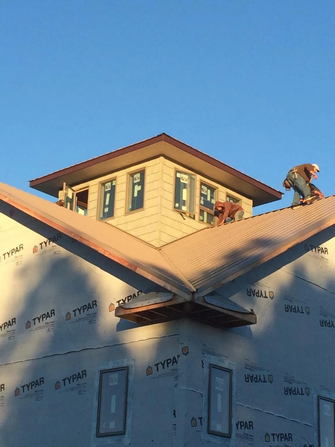 Roofers working around a rooftop cupola on a new metal roof at sunset — Roof Waterproofing in Jenison by Roofing Brothers